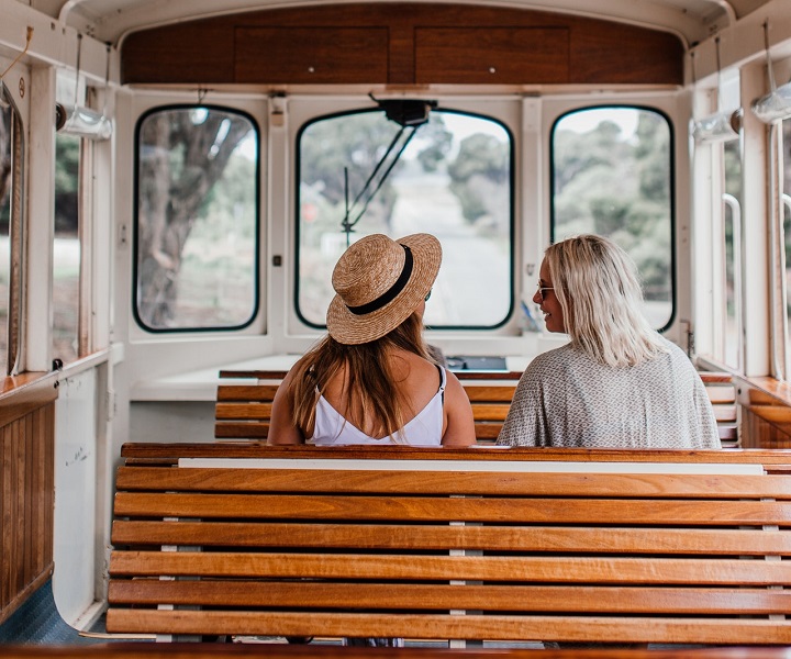 two female friends chatting on a bench inside a commercial boat, with their backs to the viewer