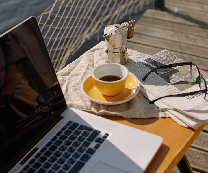 a laptop and coffee on a pier in the sunshine