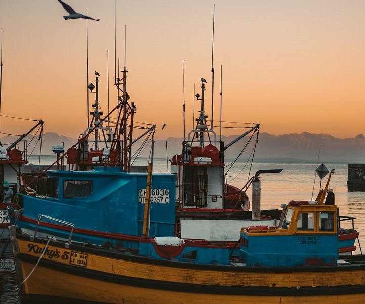 close up of a small fishing boat in harbour witha sunset behind