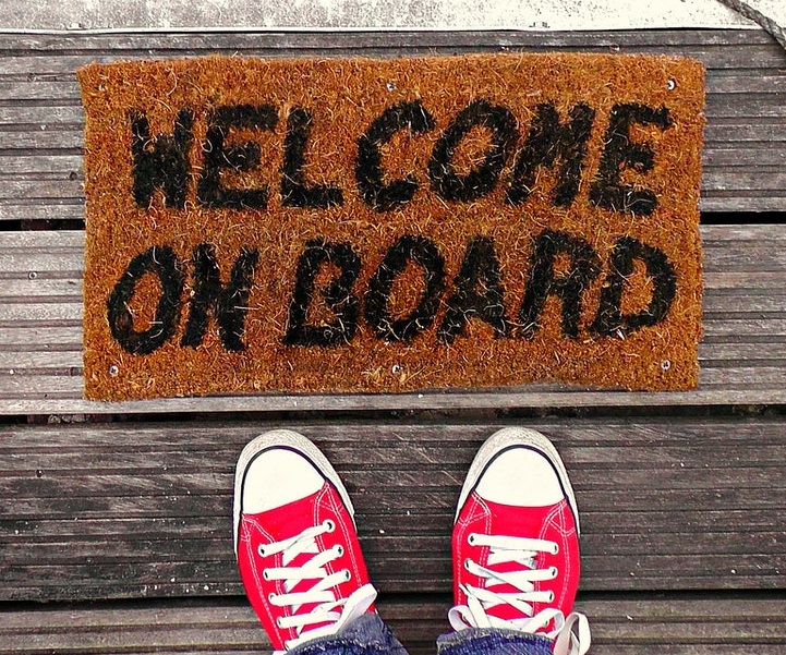 a pair of feet next to a 'welcome on board' door mat