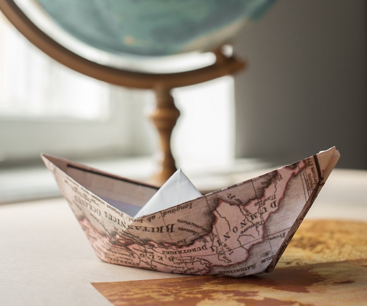 an origami paper boat made from a map sat on a desk
