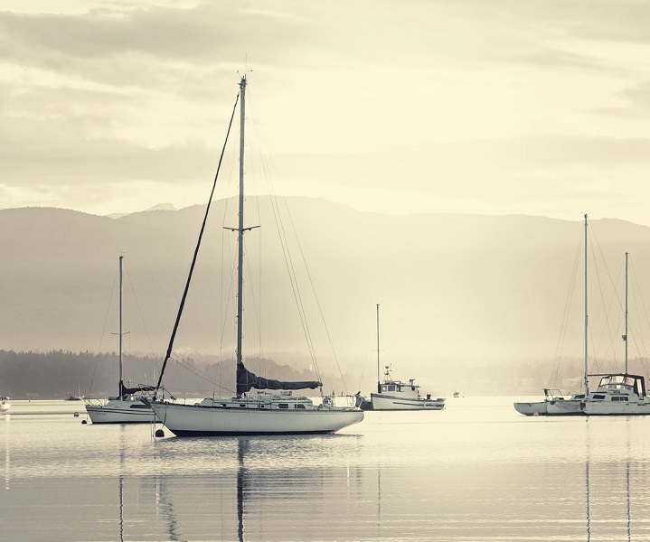 a scenic view of a yacht moored in a marina on a misty morning